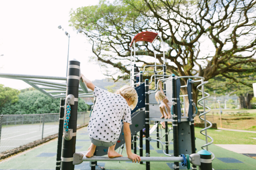 siblings playing on the tall playground at nuuanu valley park