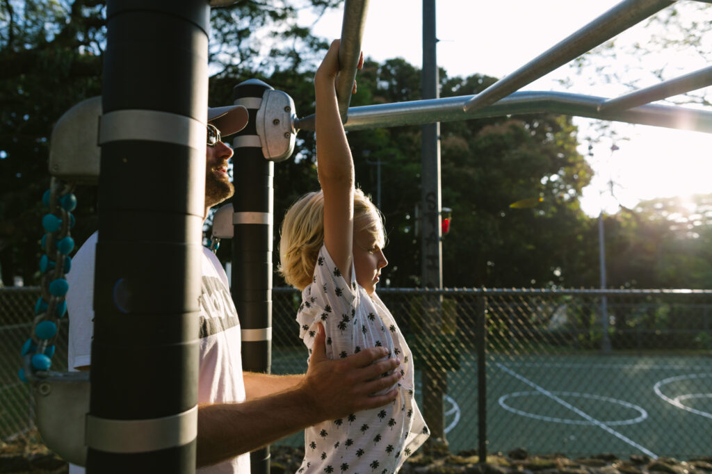 dad helping son across the monkeybars at a playground in nuuanu oahu