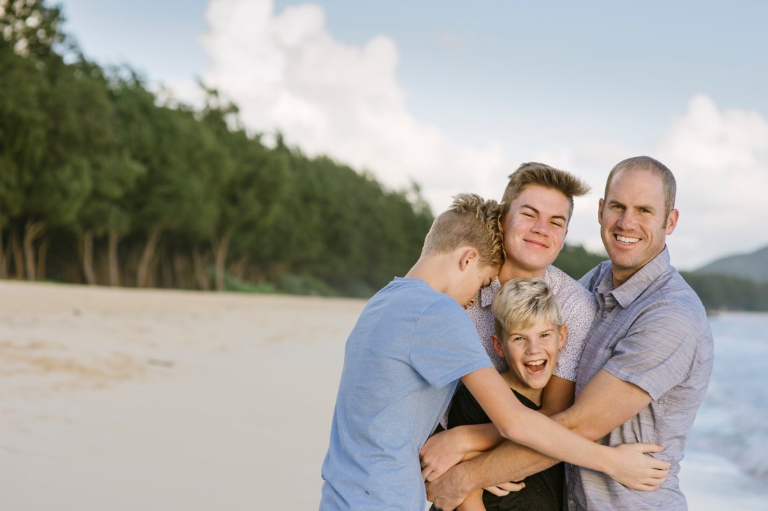 dad and sons hugging on the beach in oahu hawaii
