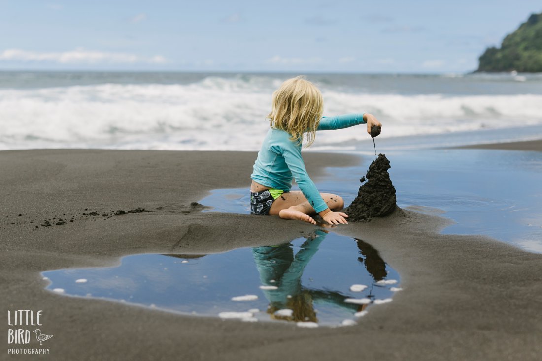 girl in waipio making a black sand castle