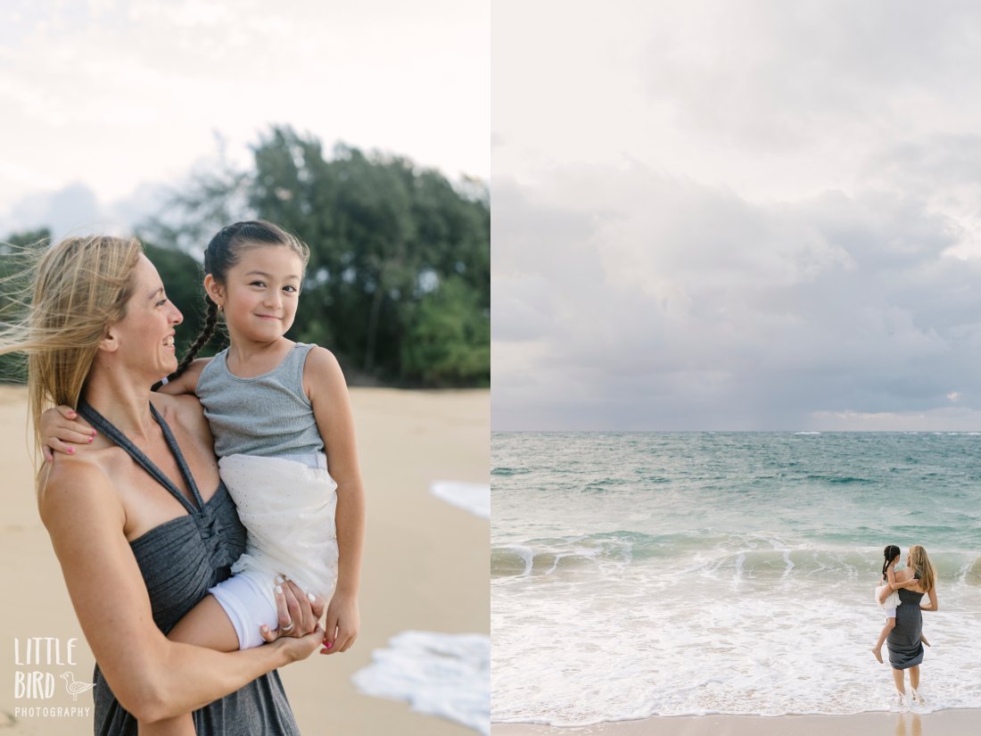 mom and daughter hugging under moody skies at a beach in hawaii