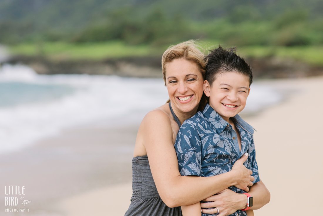 mom giving son a big hug on a beach in hawaii