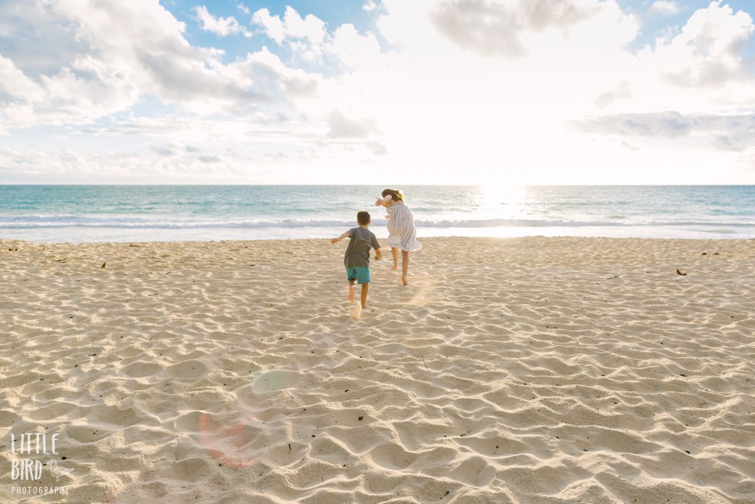 kids running toward the ocean at sunrise during a family beach photoshoot