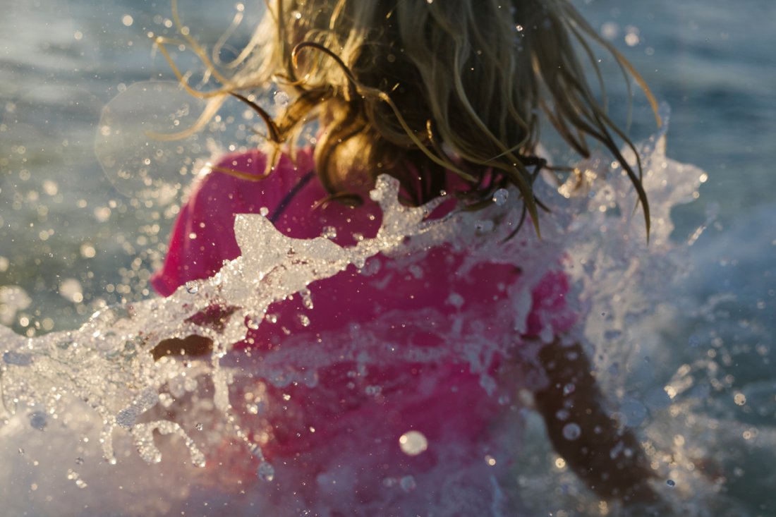 closeup of girl playing in waves at sunset