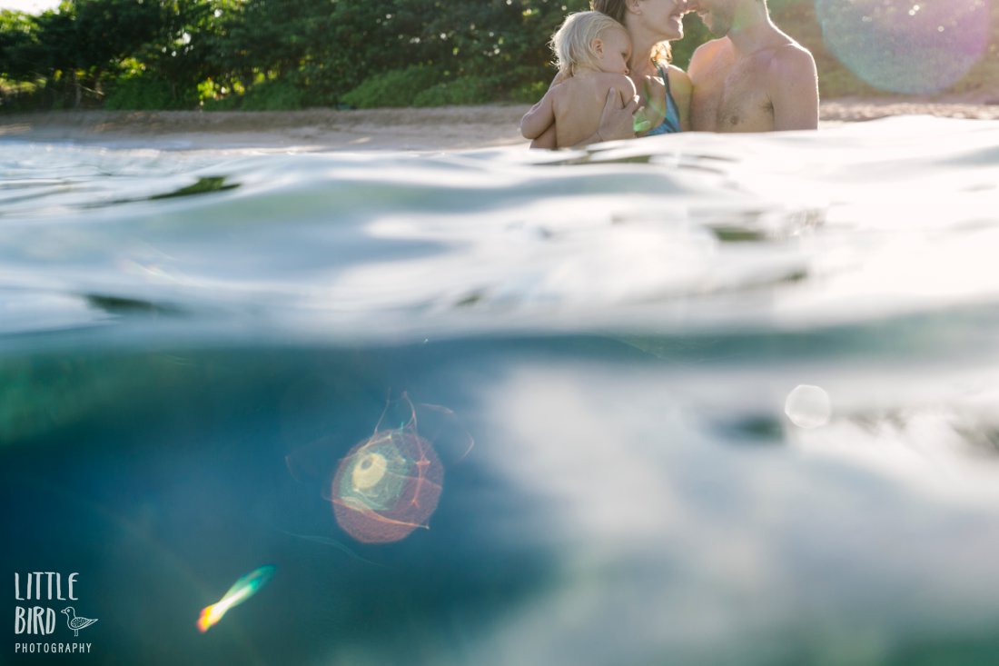couple with a baby snuggling in the water in kihei maui during a beach photoshoot