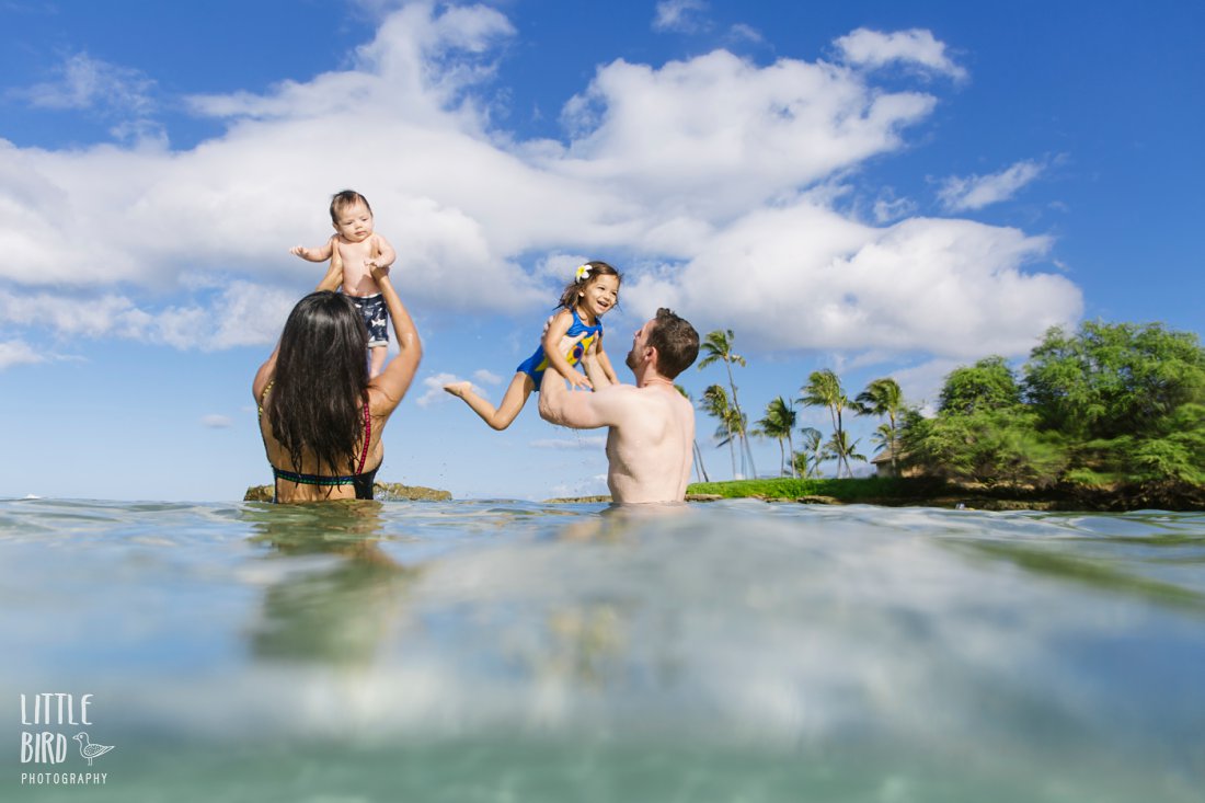 family plays in the clear blue water of hawaii