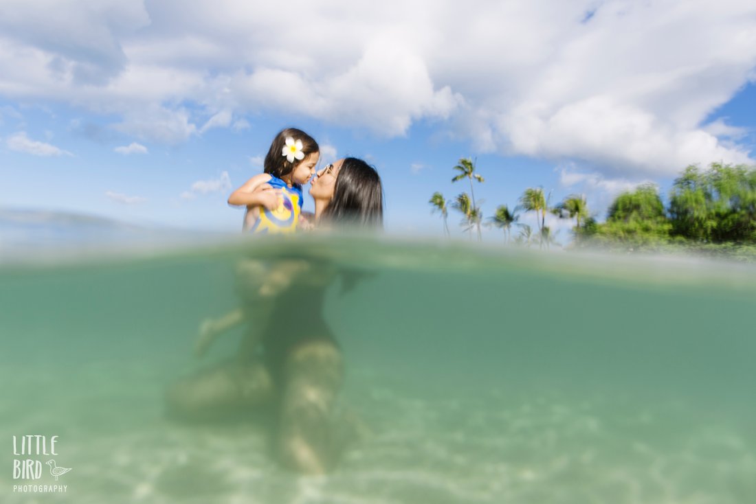 mom kisses daughter while in the water in hawaii