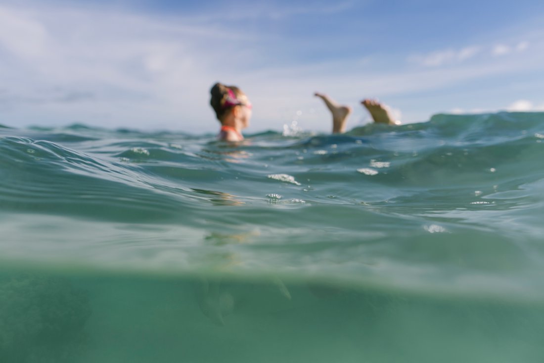 dad and daughter swimming in clear blue waters in hawaii