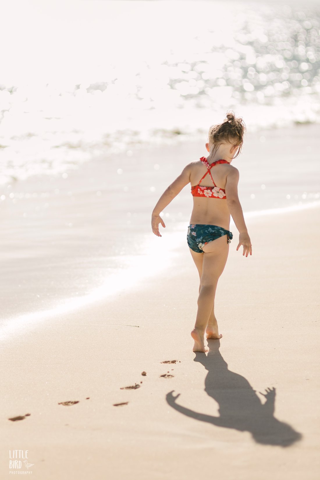 girl tiptoes on the beach in hawaii during fun oahu family photoshoot