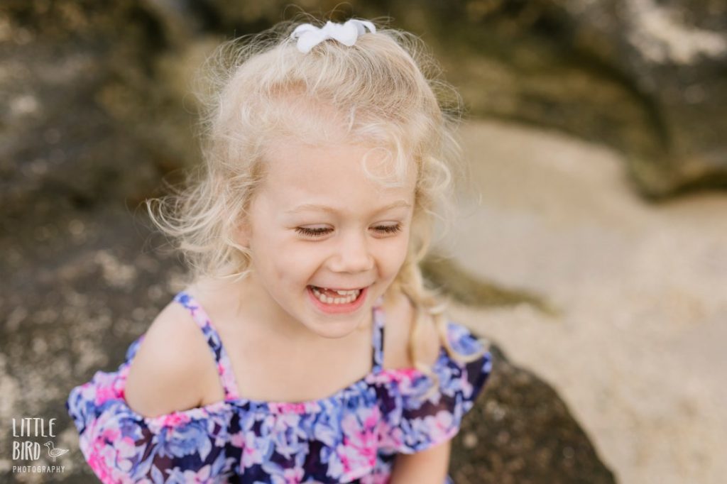 little girl laughs during a family portrait session at a beach in hawaii