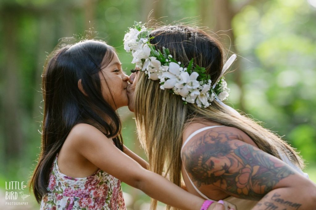 mom and daughter share a silly kiss in a hawaiian rainforest