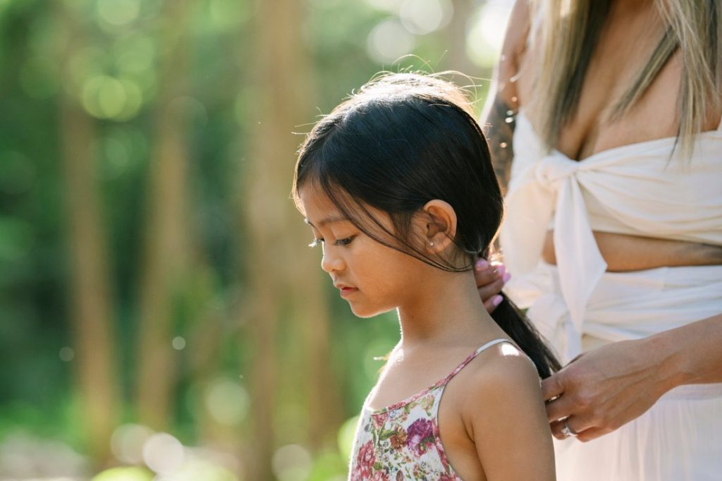 mom fixing daughters hair during a photo shoot in the forest
