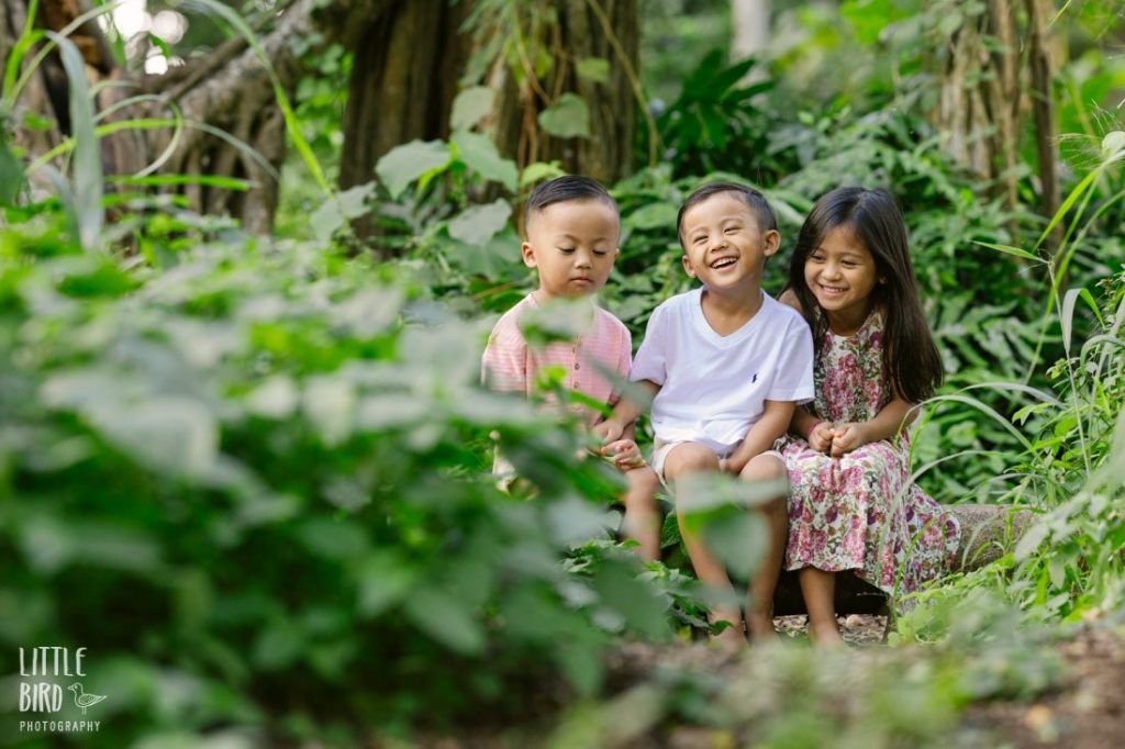 siblings sitting on a log during a family photo shoot in hawaii