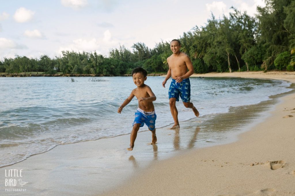 dad chasing son along the beach at kawela bay oahu
