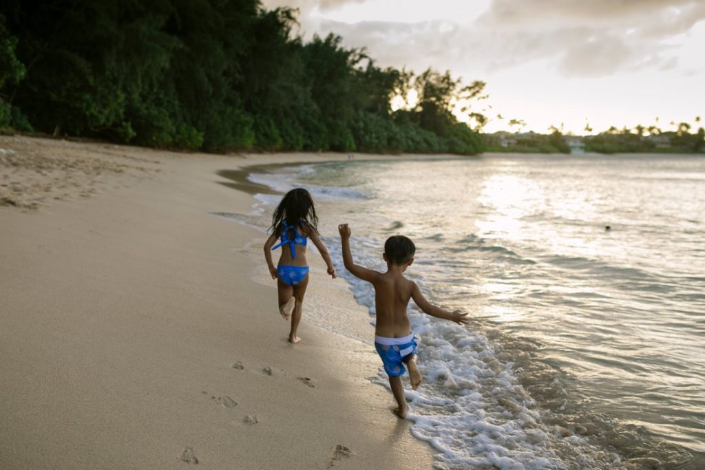 kids running on the beach at sunset in hawaii
