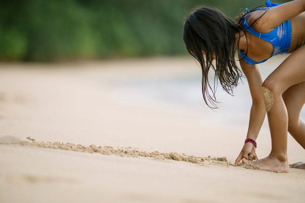 girl drawing in the sand at a beach in hawaii