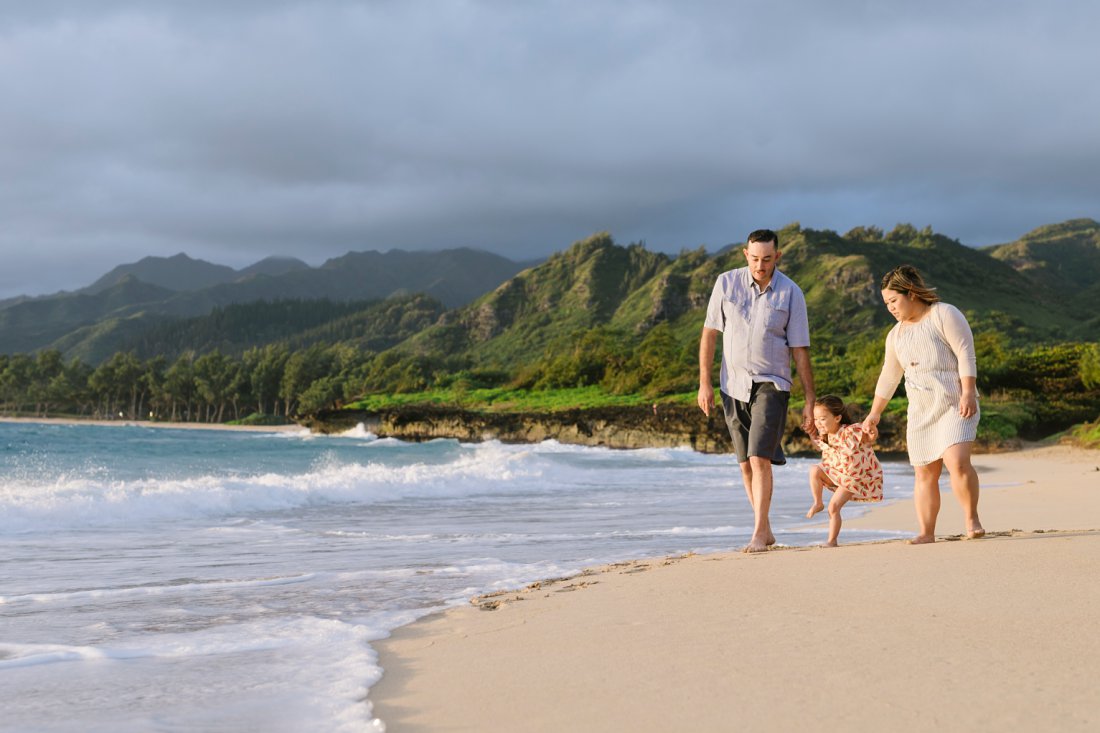family walking along the beach at sunrise in hawaii