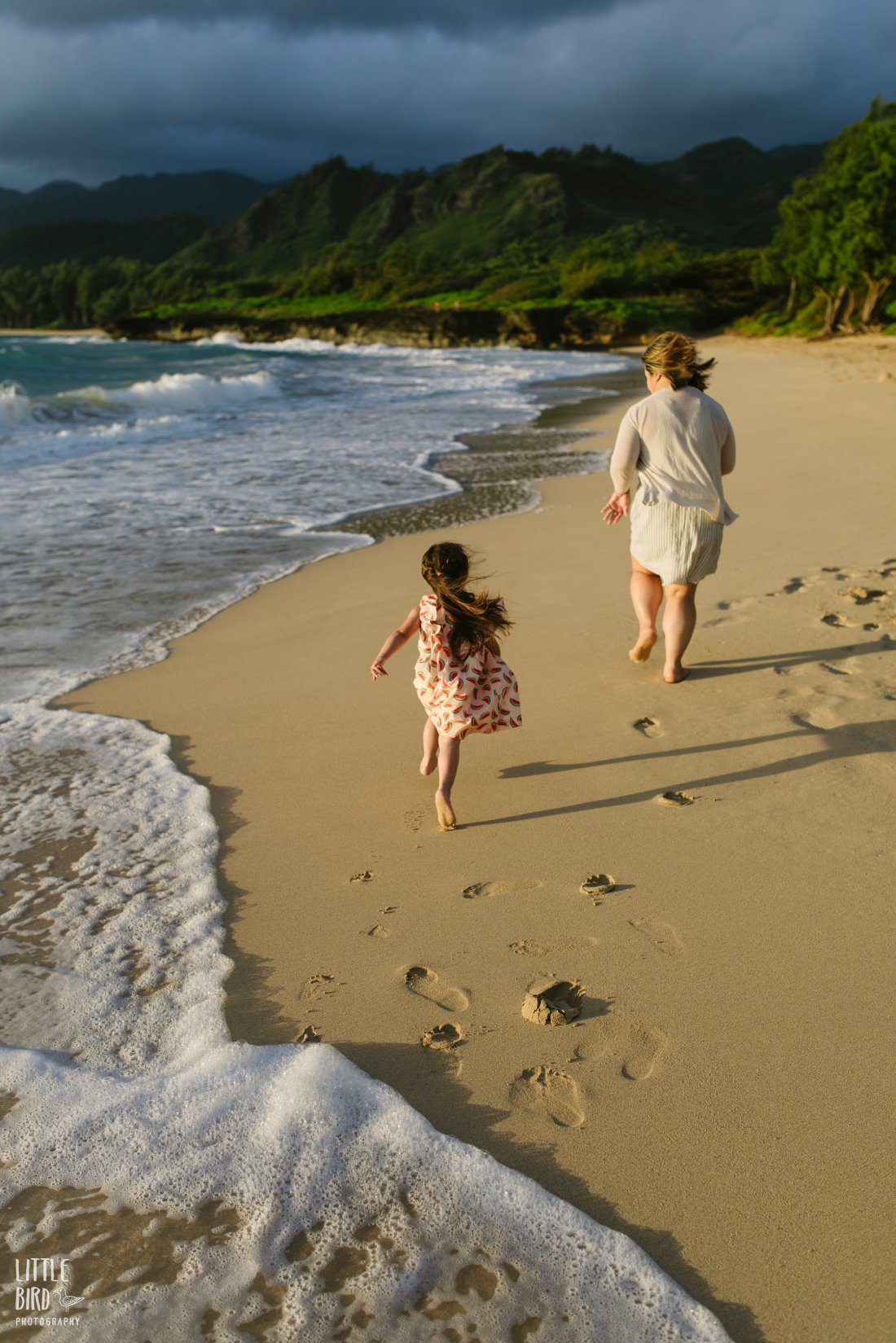 mom and daughter run down the beach during photoshoot by little bird photography