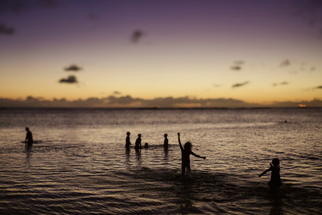 silhouette of kids playing in the water at sunset in hawaii