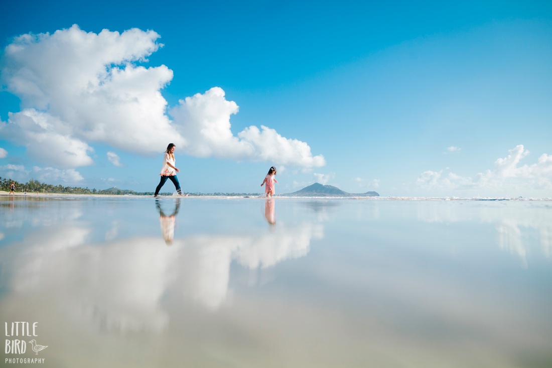 mom and daughter at kailua beach with reflections of the sky during a photo session by little bird photography