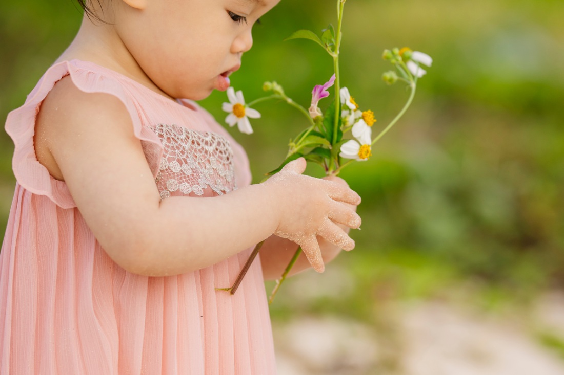 baby with a bouqet of flowers at the beach in hawaii