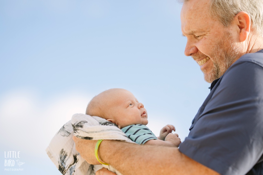 grandpa looks lovingly at new grandson during a family photo shoot in oahu