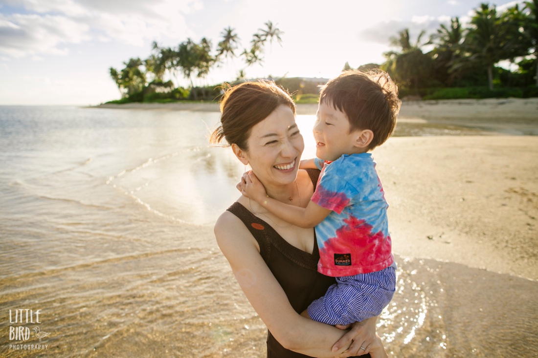 mom and son share a laugh on waikiki beach during a photoshoot