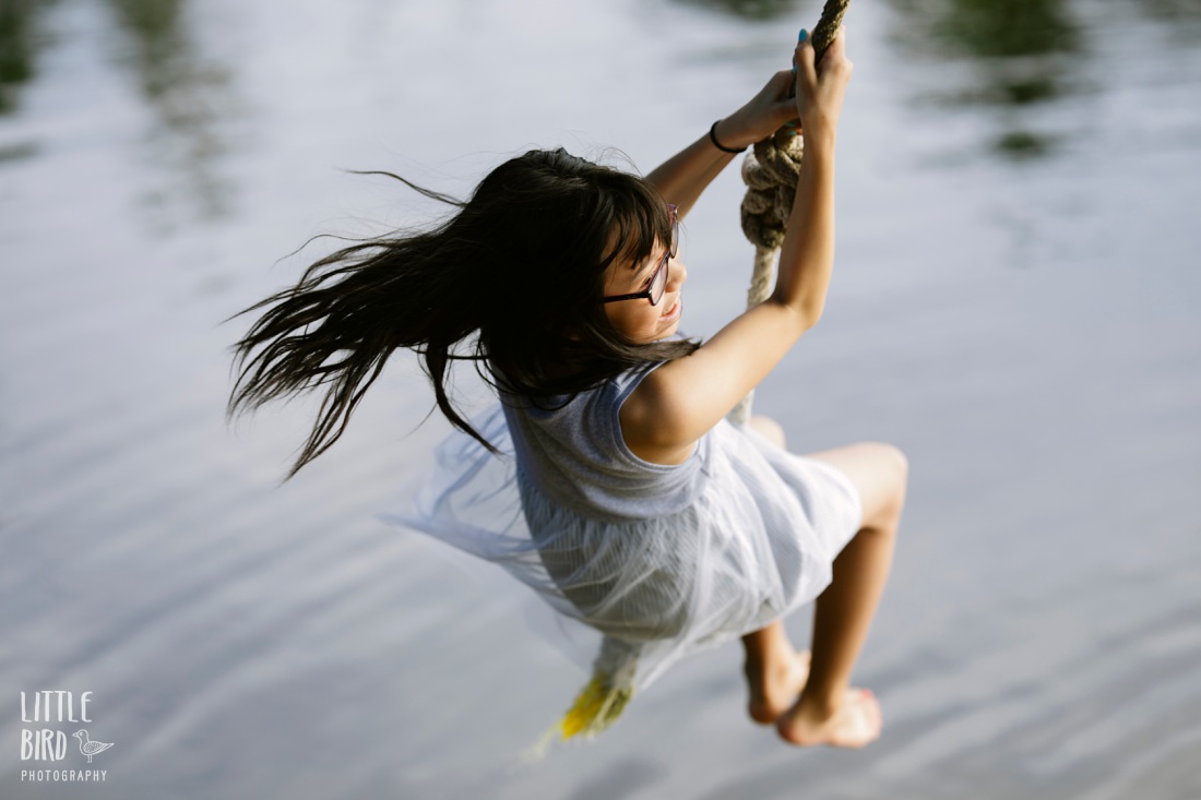 girl swinging on a rope swing during a fun family photo session by little bird photography