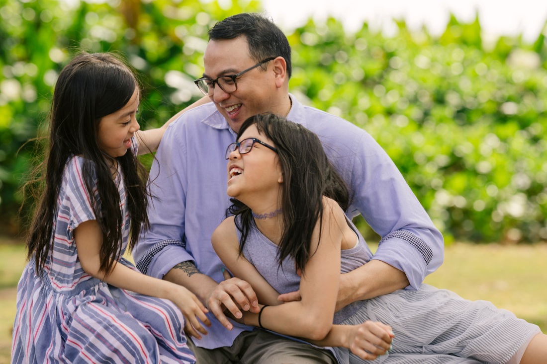 dad and daughters hare a laugh during an oahu family photo session
