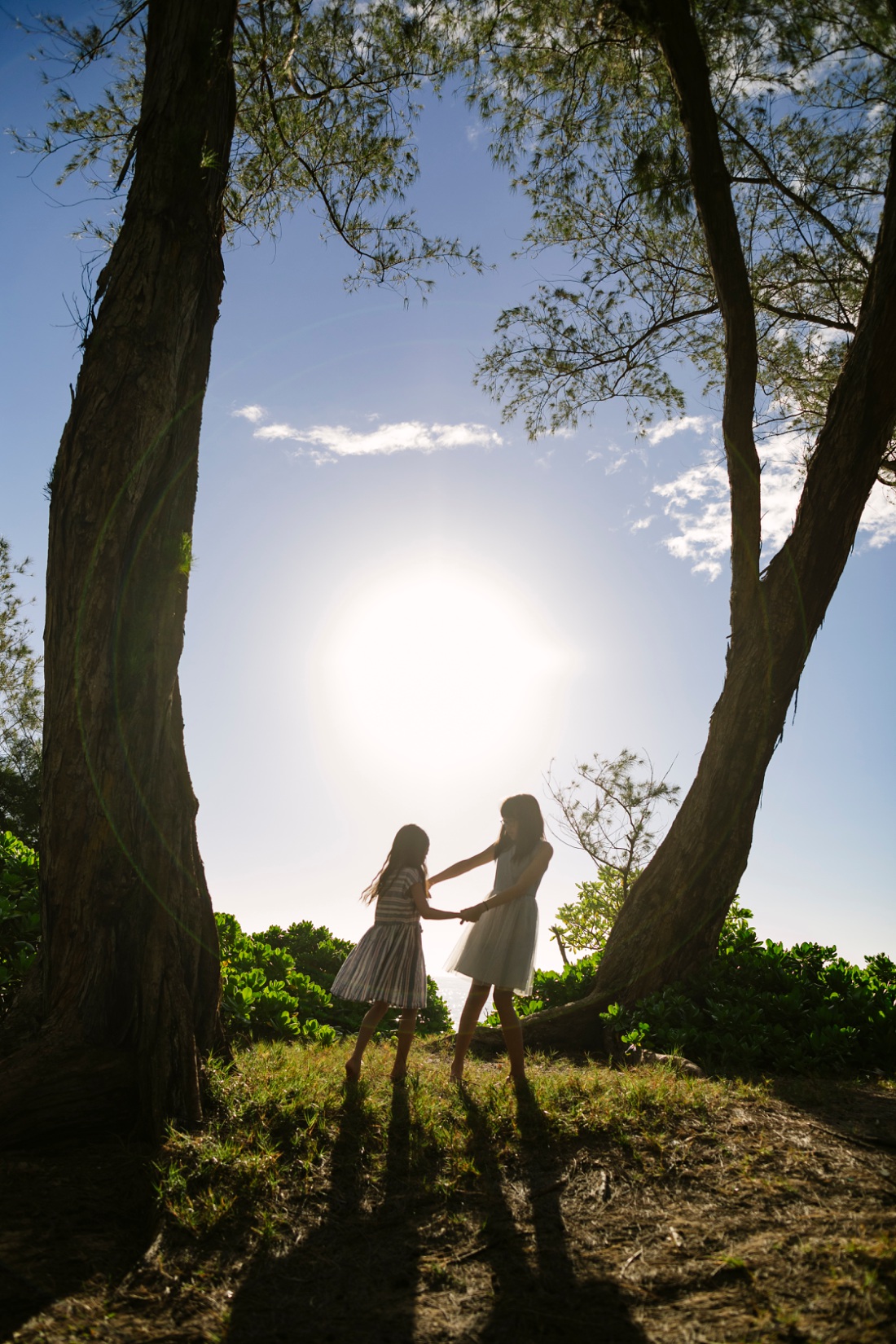 silhouette of girls playing under the trees at sunrise by a laie photographer