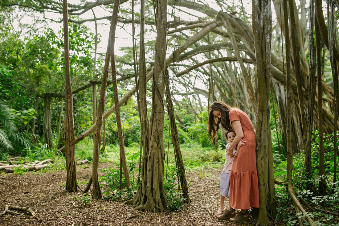 mom hugging son beneath a banyan tree in oahu for a family photo session