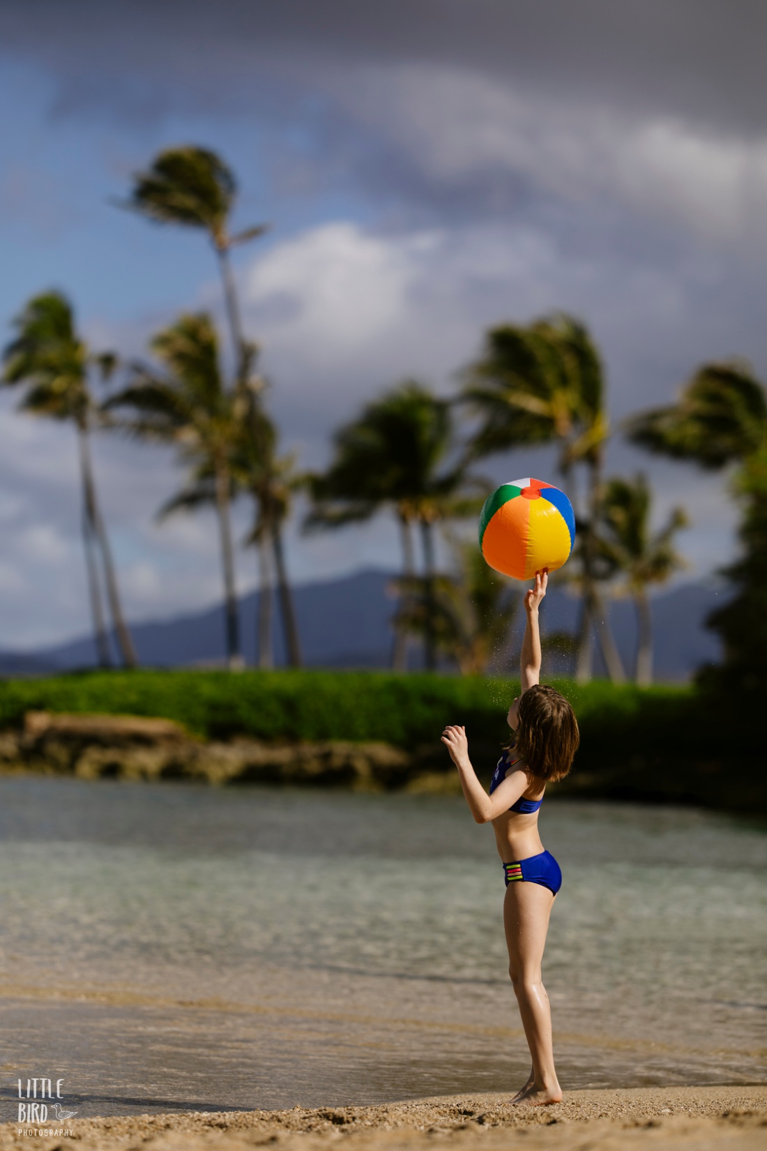 girl playing with a beach ball during a portrait session in hawaii 
