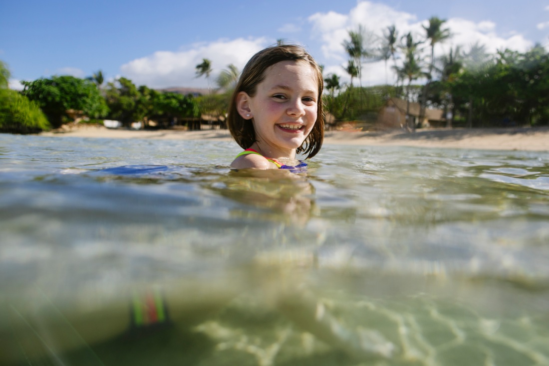 girl swimming in the clear blue waters of paradise cove in koolina oahu