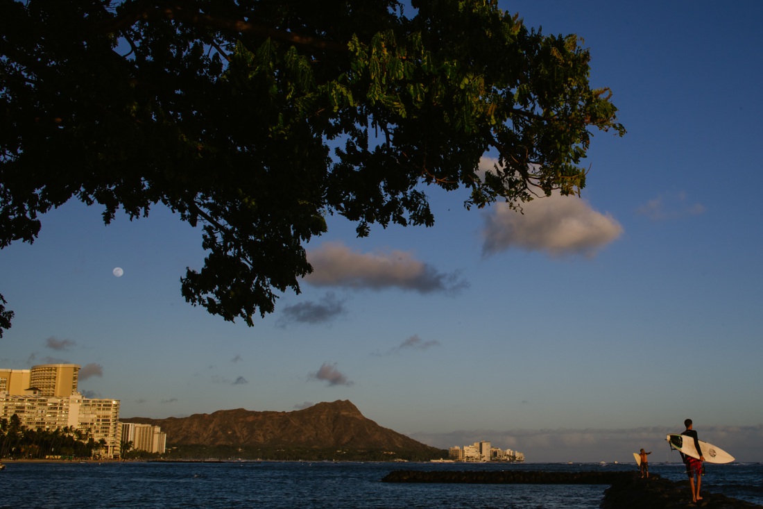 view of diamond head with surfers and a full moon
