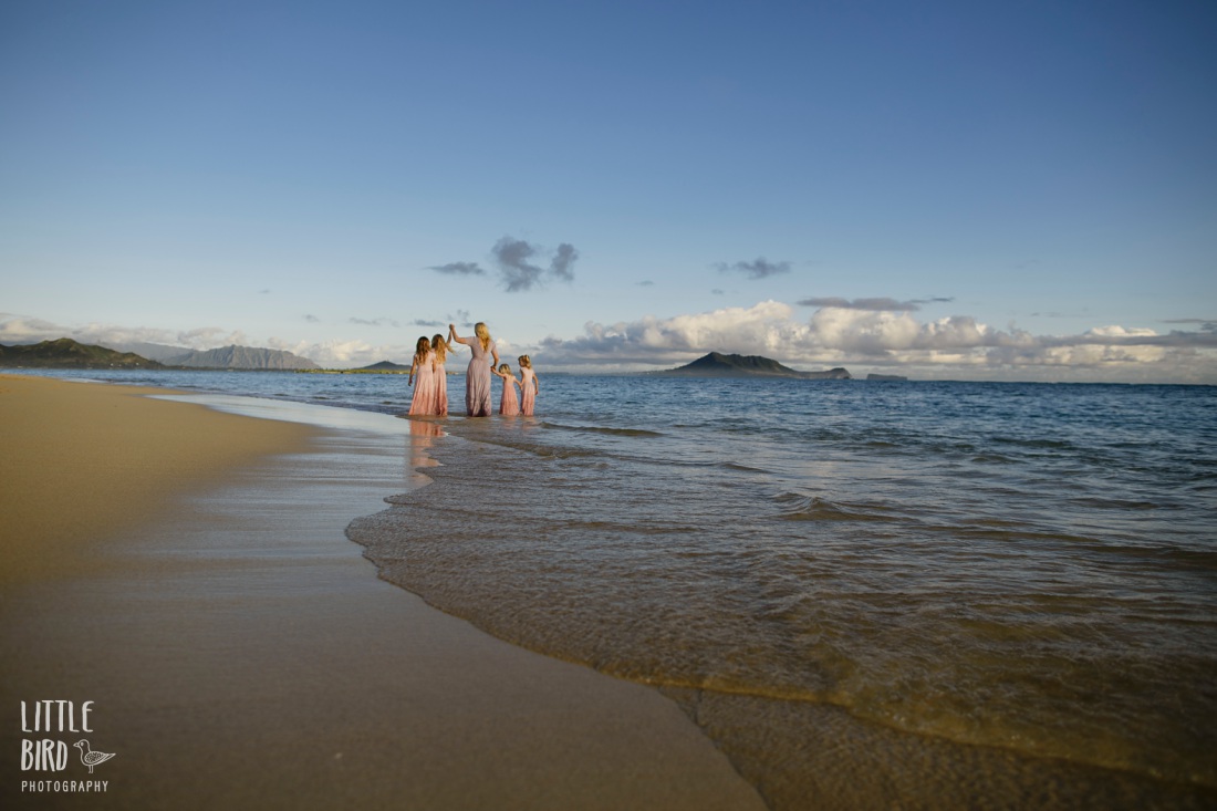 mom and daughters walking along the shore of lanikai beach during a family photo session in oahu