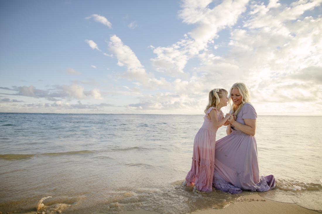 mom and daughter sharing a laugh on the beach in hawaii at sunrise