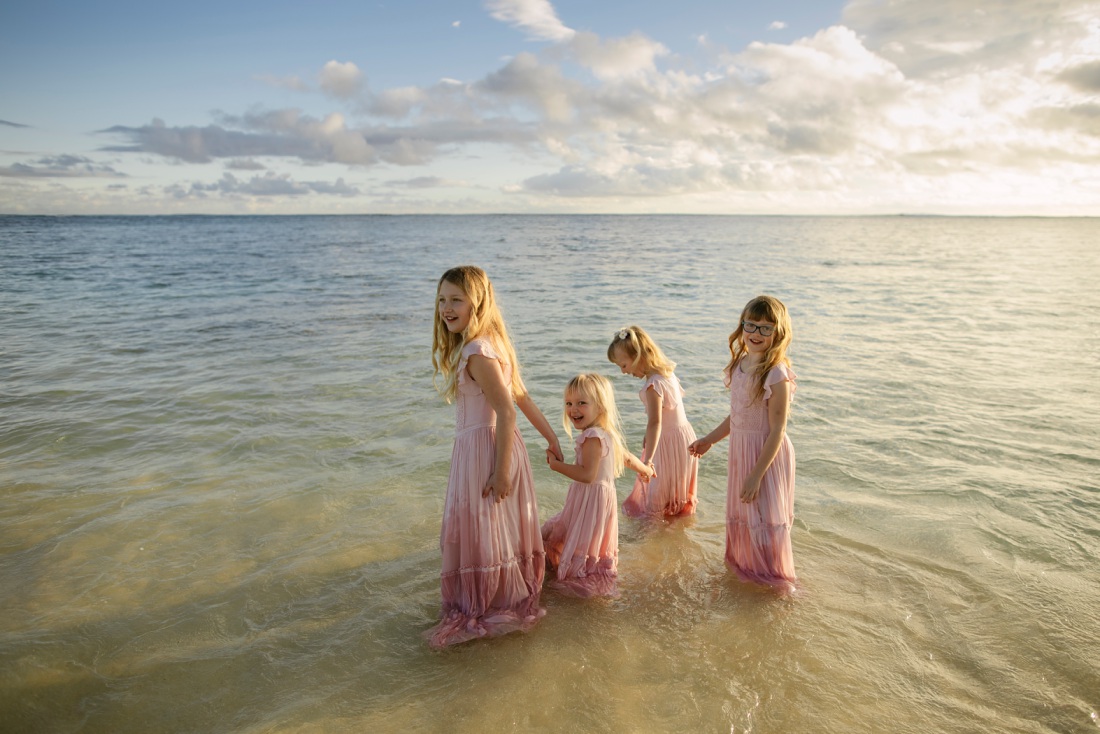 sisters with matching joyfolie dresses playing in the water in hawaii