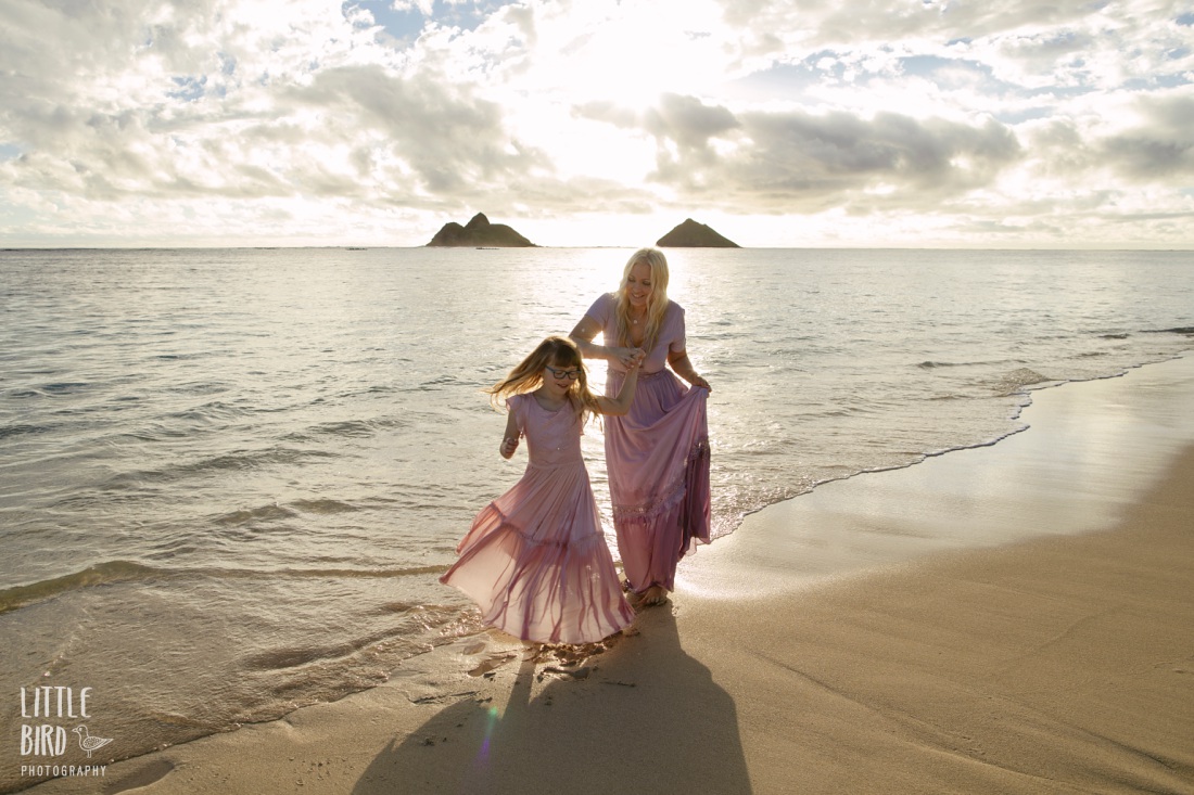 mom spinning daughter at sunrise in lanikai during a family photo session
