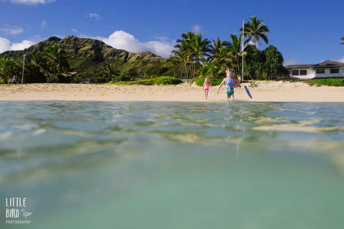 excited sisters running to the water at lanikai beach during photo session by little bird photography