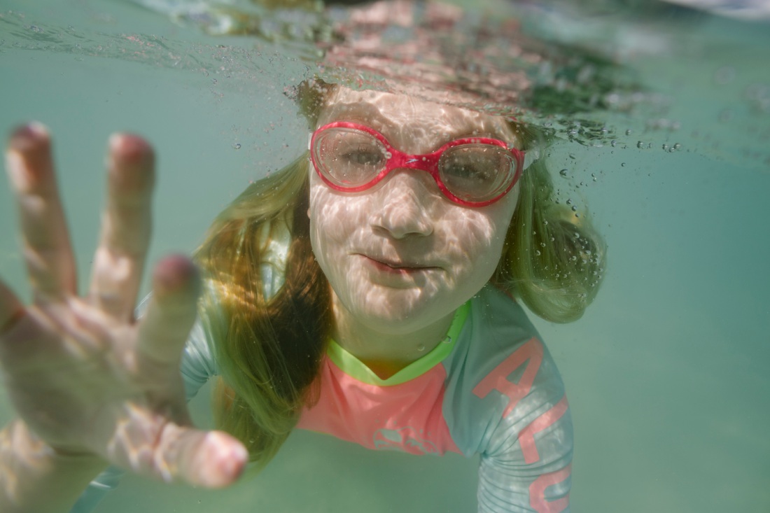 girl with goggles swimming underwater in hawaii