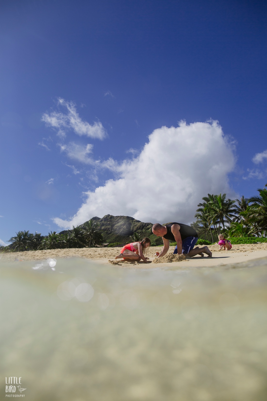 dad helping daughters make a sand castle at lanikai beach hawaii during a Family Photography and Films session