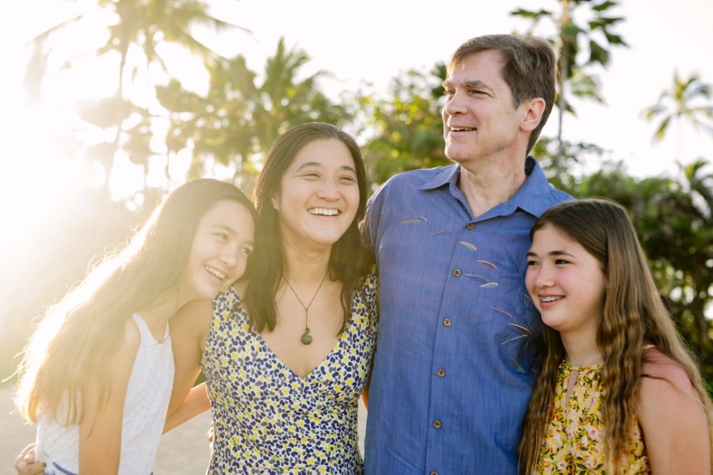 portrait of a happy family with palm trees and sun flare in hawaii