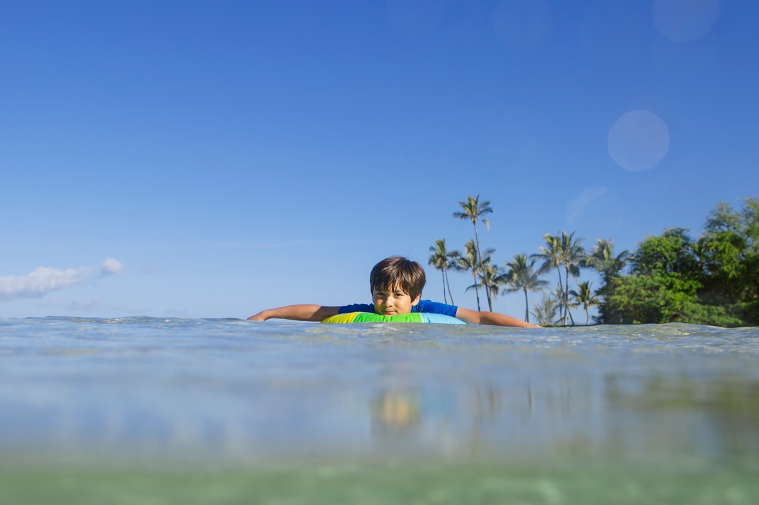 boy floating in an inter-tube at paradise cove in koolina oahu