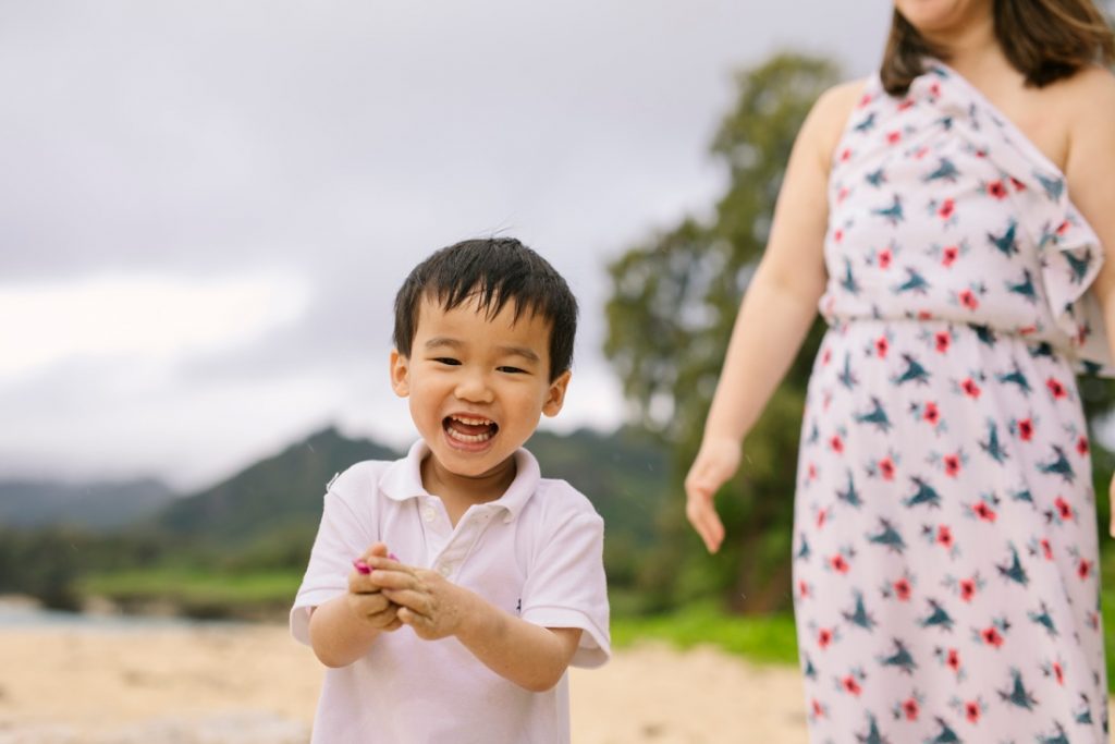 little boy laughing on the beach in hawaii