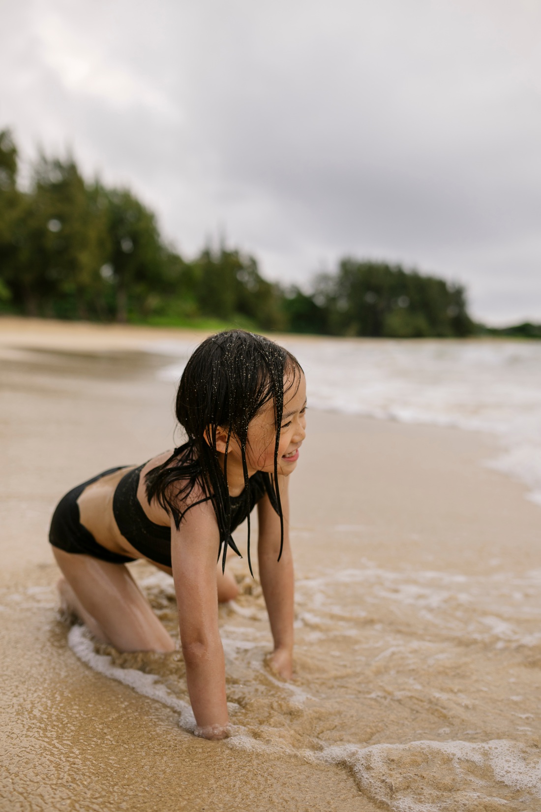 girl playing in the waves at laie beach during a family photo session