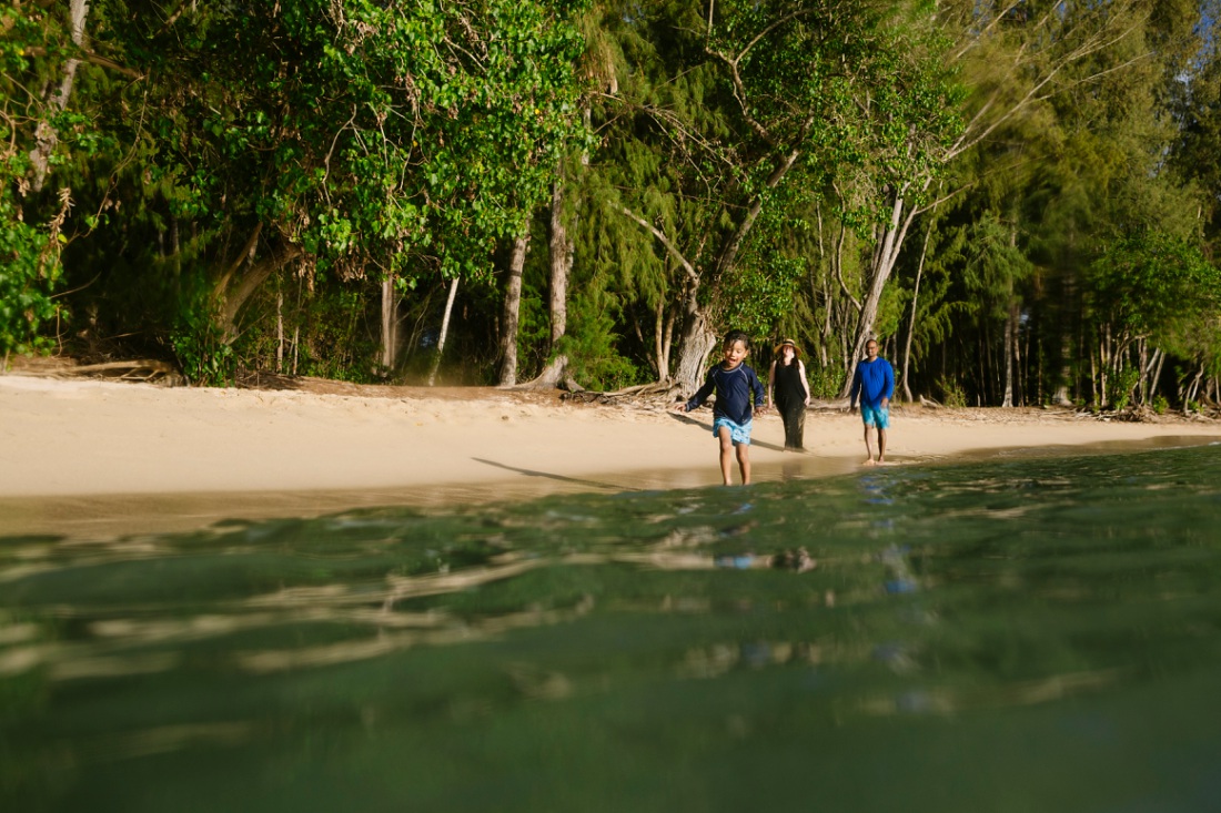 family walking along the beach at kawela bay