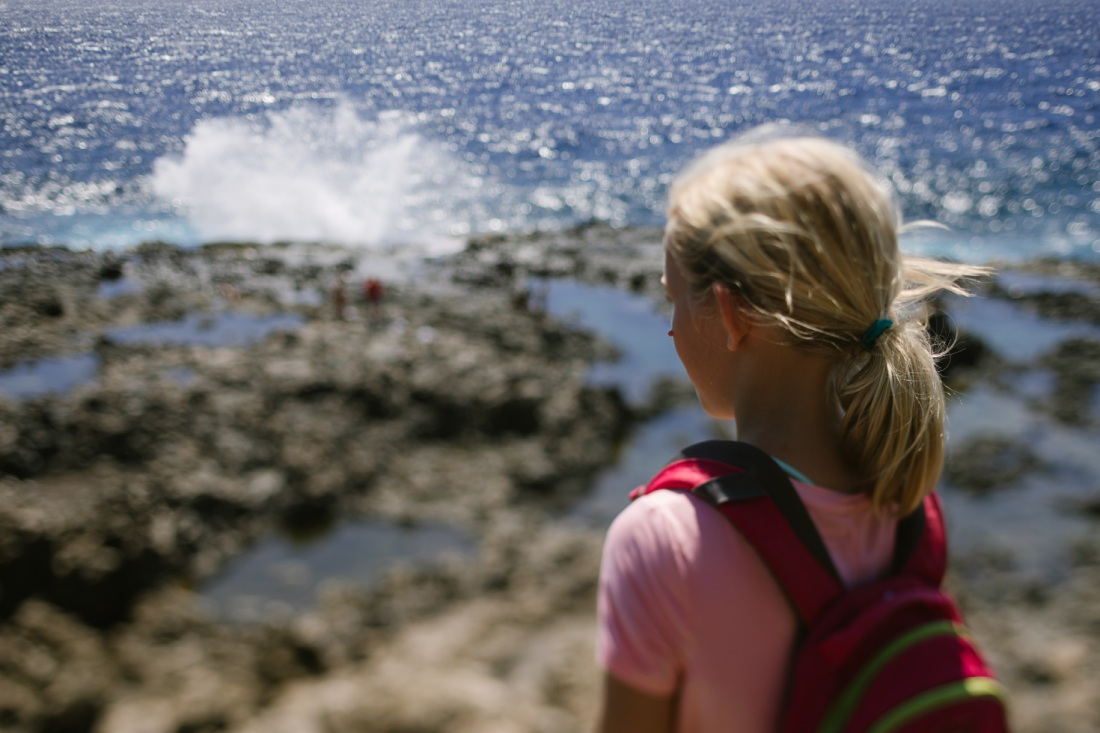 girl watching waves splash against the rocks at the makapuu tide pools
