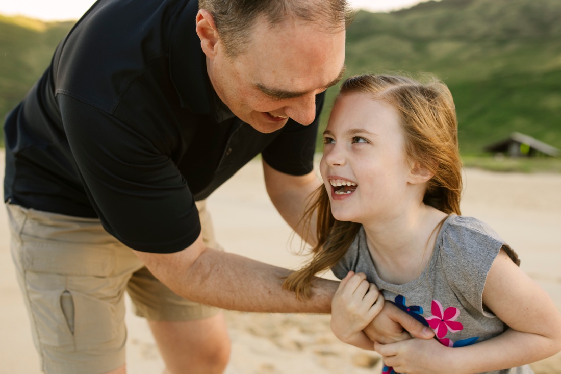dad and daughter share a laugh during a family photo session in hawaii