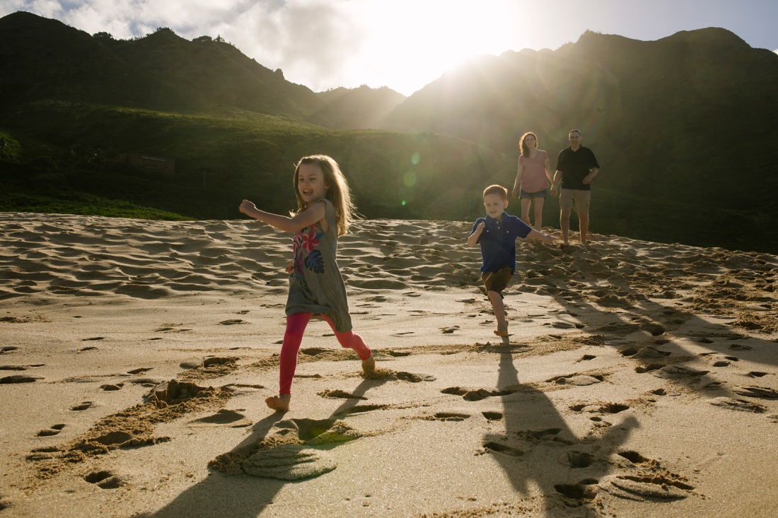 family running on the beach with mountains in the background in hawaii