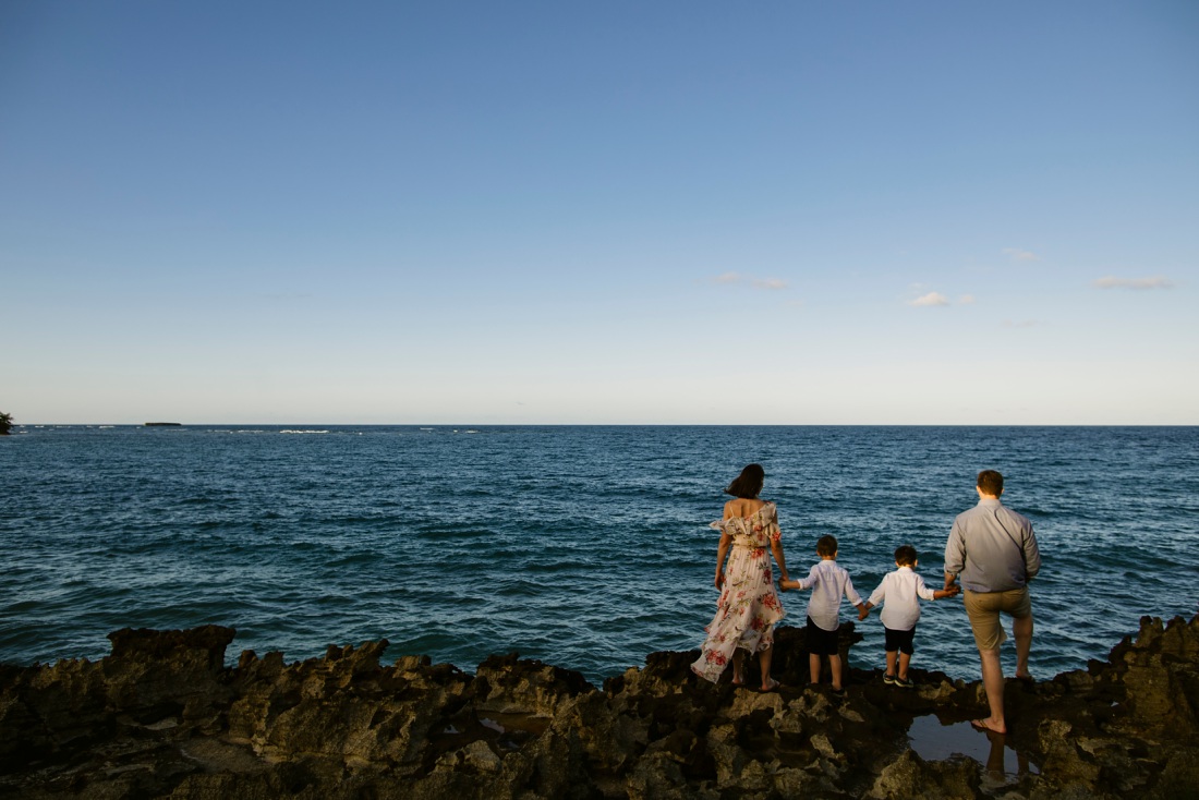 family watching the ocean from the cliffs at laie beach park in hawaii